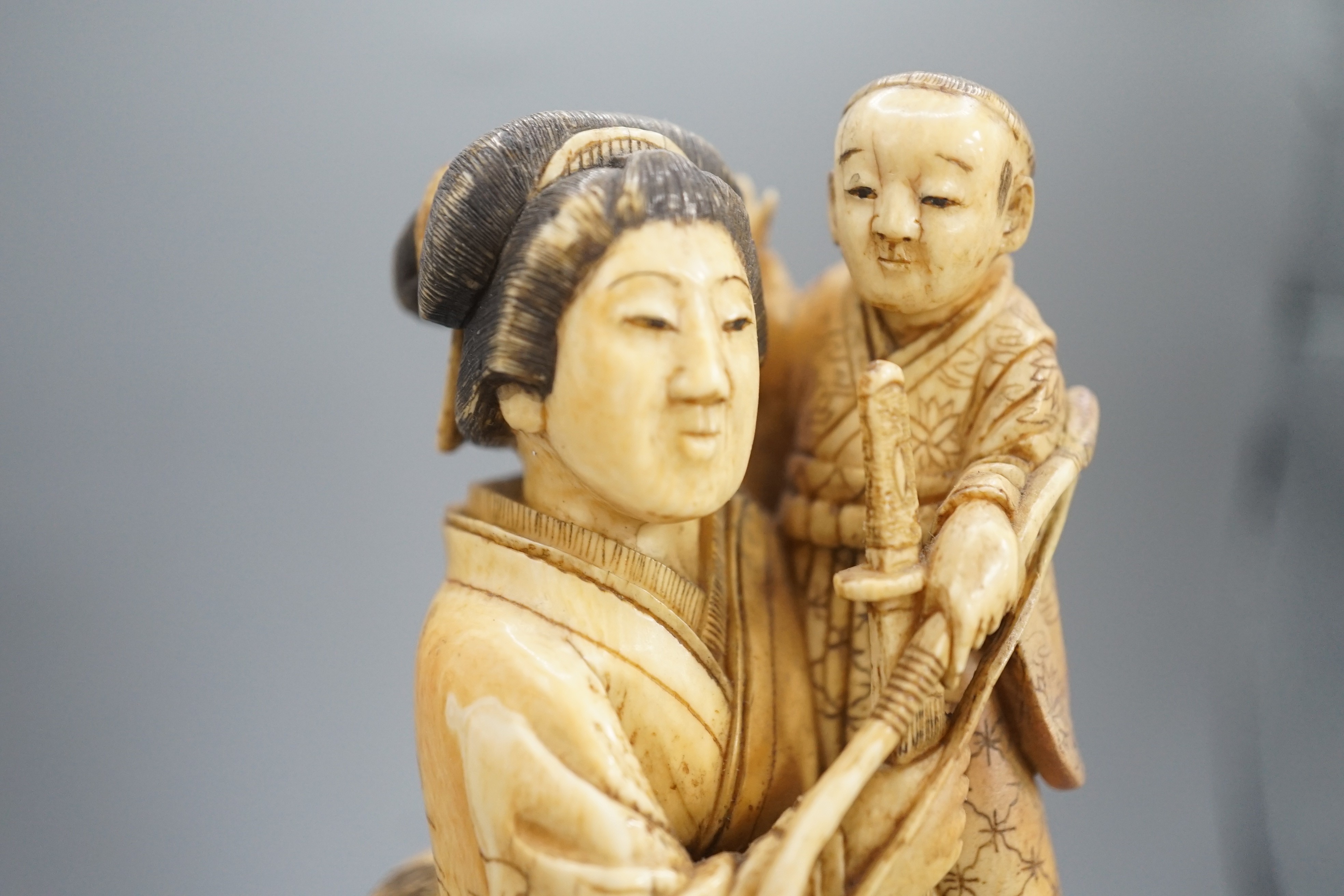 A Japanese ivory okimono of a lady holding a boy with a bow and arrow, Meiji period, restoration 12cm, wood stand